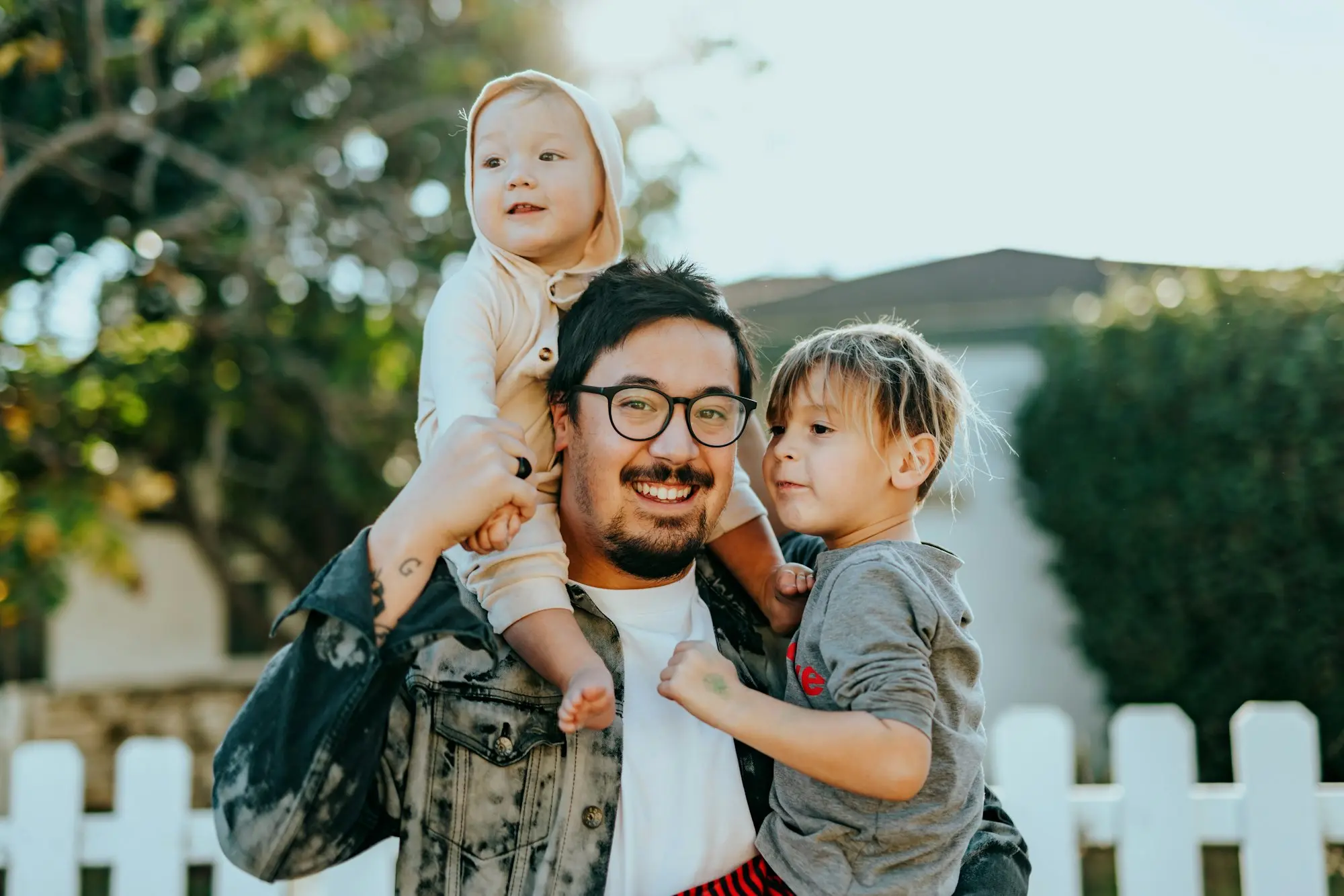 Padre sonriente al aire libre con sus dos hijos a hombros
