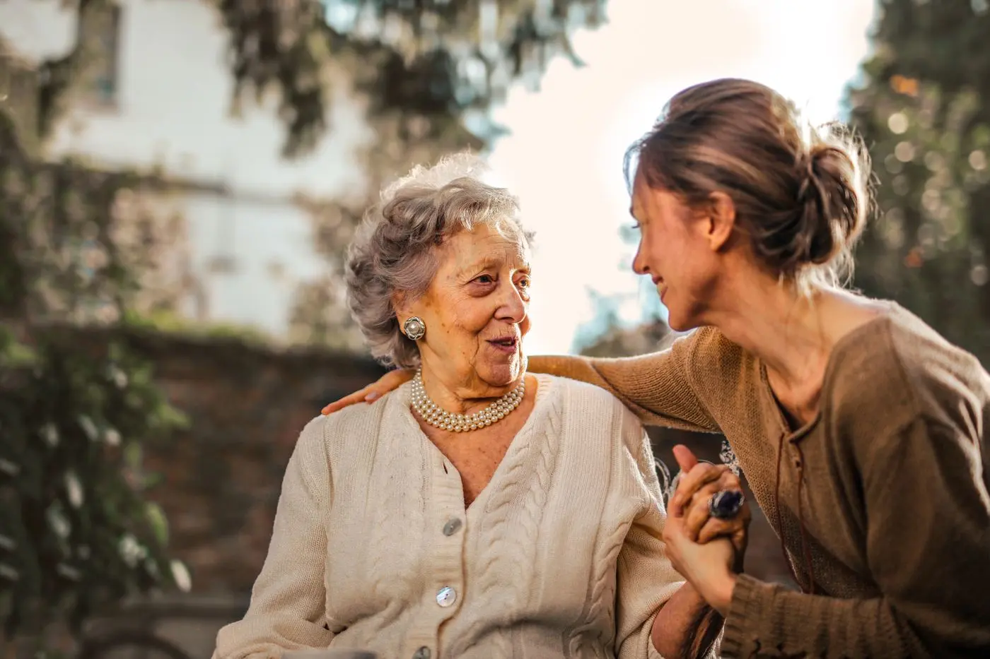 Mujer mayor sonriendo junto a una mujer joven al aire libre